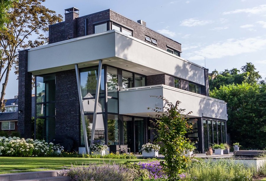 Moderne woning met donkere baksteen, witte gevelbanden en grote ramen
